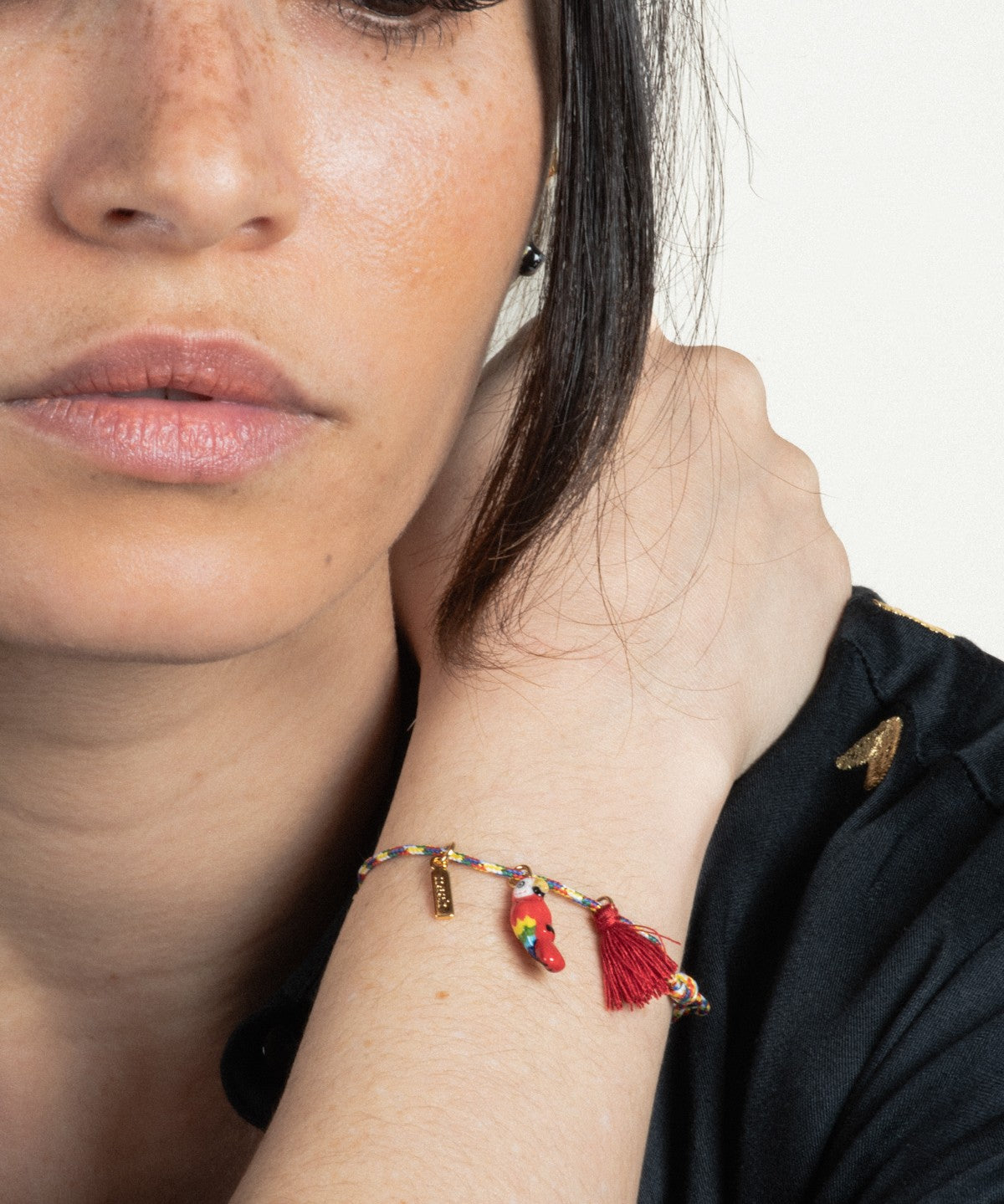 bracelet cordelette oiseau perroquet rouge avec pompon