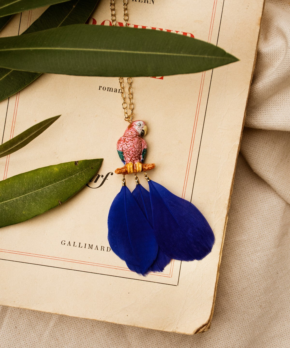 collier doré perroquet rose bleu plume bleue